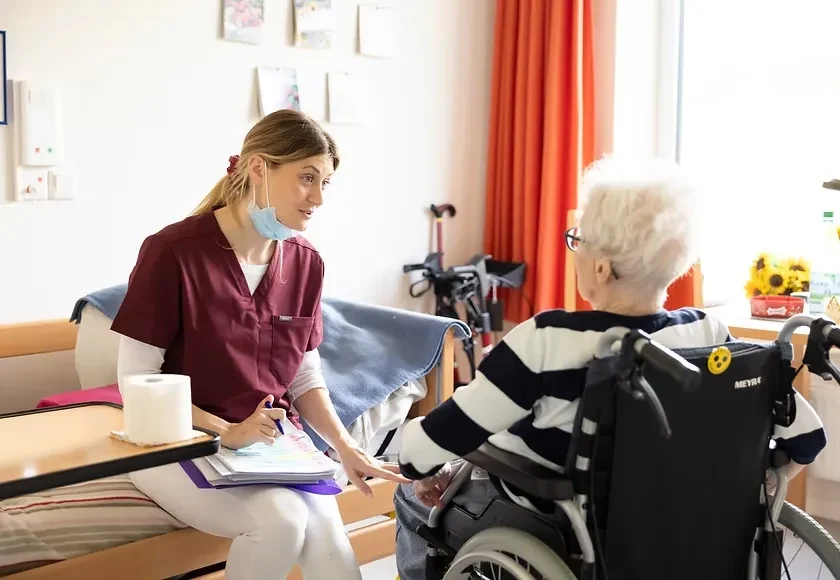 Mobile Zahnarztpraxis beim Hausbesuch: Beratung einer Patientin im Rollstuhl in der Pflegeeinrichtung