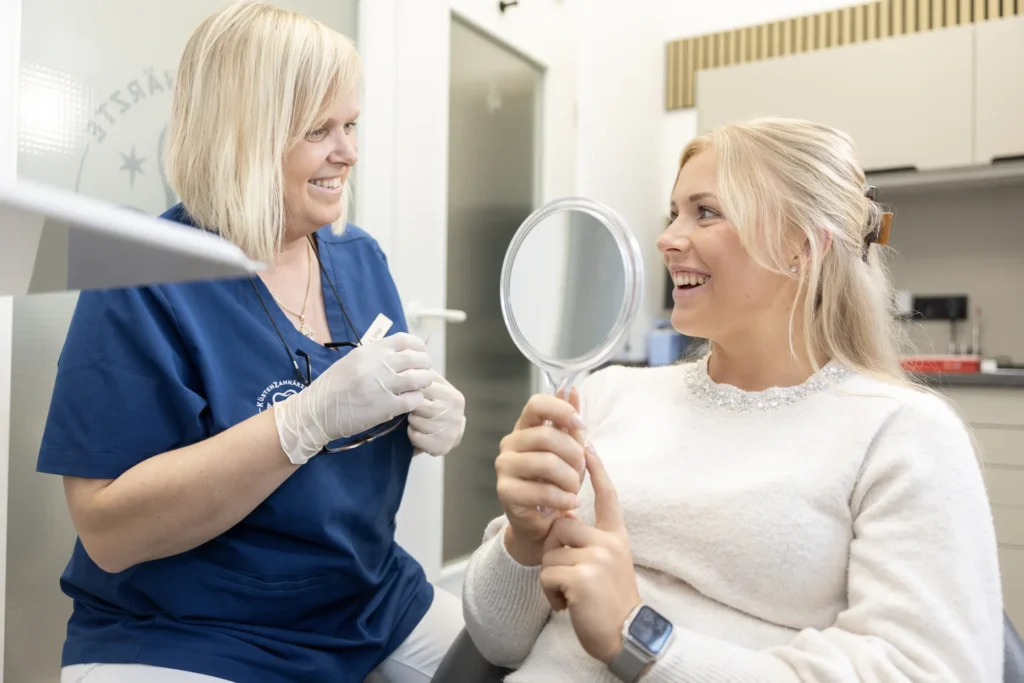 Veneers in Scharbeutz: Patientin prüft das Ergebnis im Handspiegel
