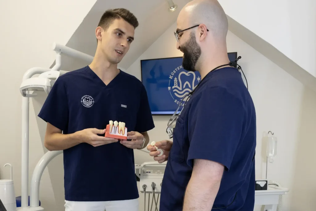 Behandlerteam der KüstenZahnärzte am Implantatmodell in Scharbeutz